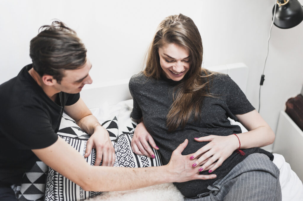 man-touching-pregnant-woman-s-belly-bedroom
