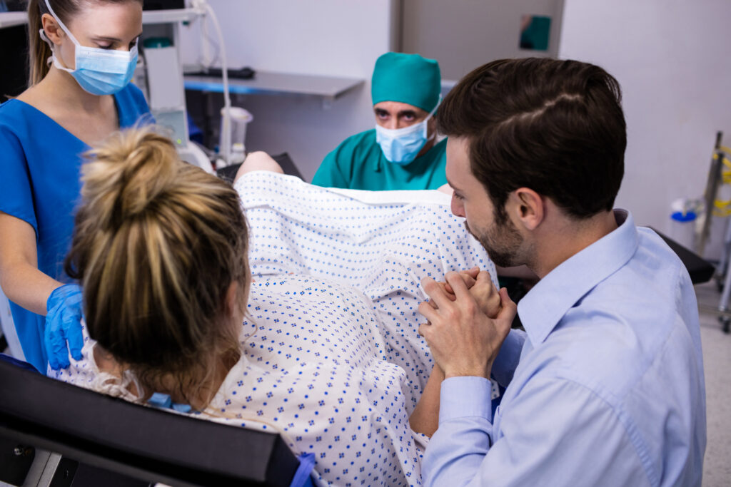 medical-team-examining-pregnant-woman-delivery-while-man-holding-her-hand