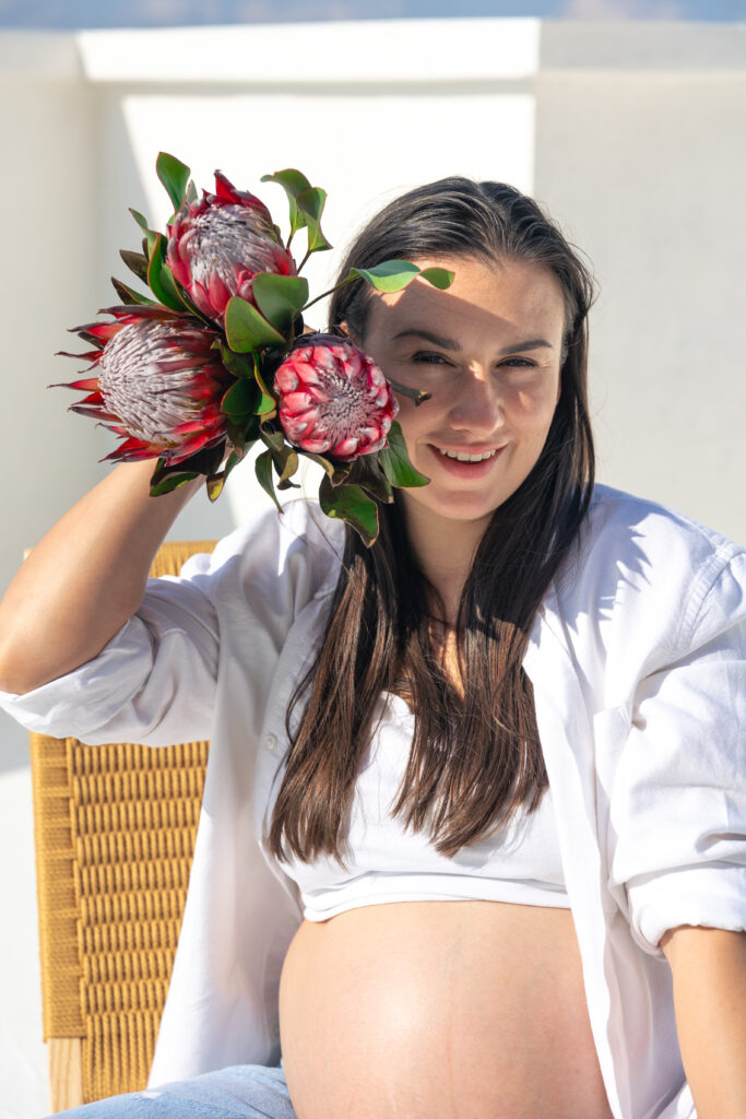 Pregnant woman with protea flowers. Concept of style and pregnancy.