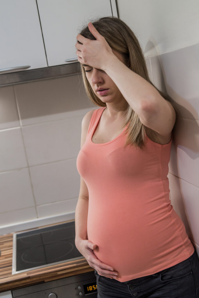 Struggling with morning sickness. Depressed pregnant woman holdi
