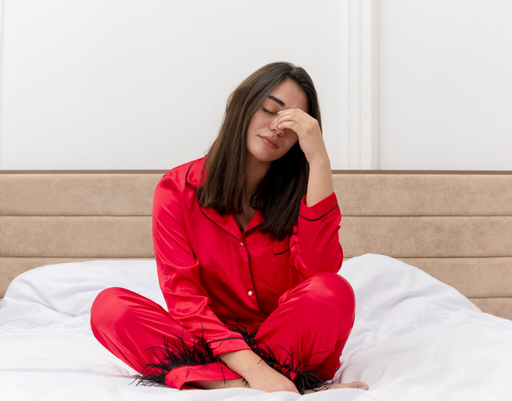young-beautiful-woman-red-pajamas-sitting-bed-looking-tired-overworked-wants-sleep-bedroom-interior-light-background
